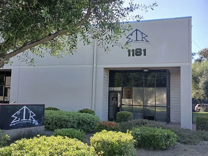 The Electric Transportation Repair building at 1181 North 4th Street, San Jose — a white single-storey unit with the angular ETR logo and the number 1181 above the entrance, and a matching ETR sign on the low wall by the road.